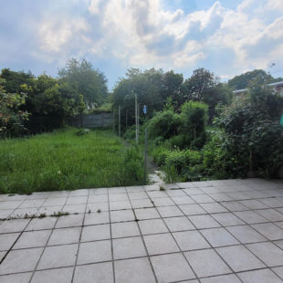 Maison de construction années 60 avec 3 chambres, jardin, parking devant la maison.